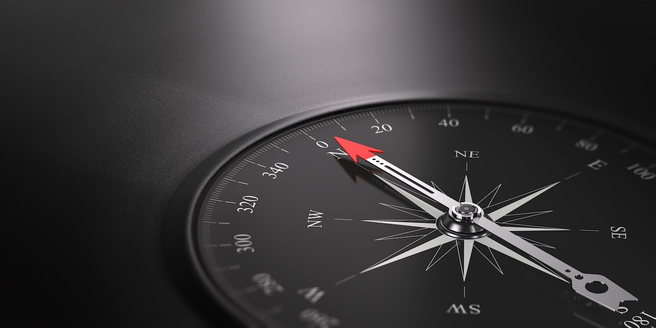 3D illustration of a compass over black background with needle pointing the north direction, free space on the left side of the image. Business orientation concept.